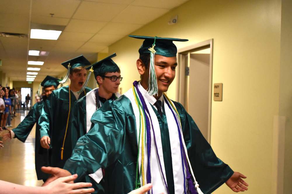 Twin Peaks Classical Academy tuition-free charter school graduates in caps and gowns walking through school hallway