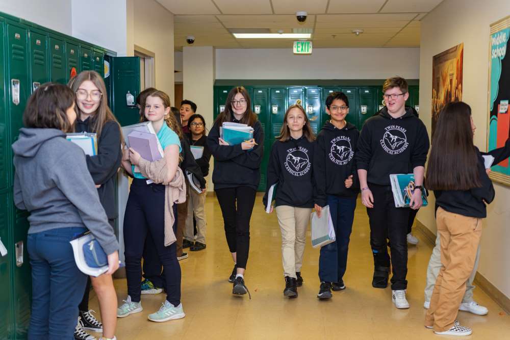 a group of 10 students walk down the hallway smiling at Twin Peaks tuition-free PK-12 charter school