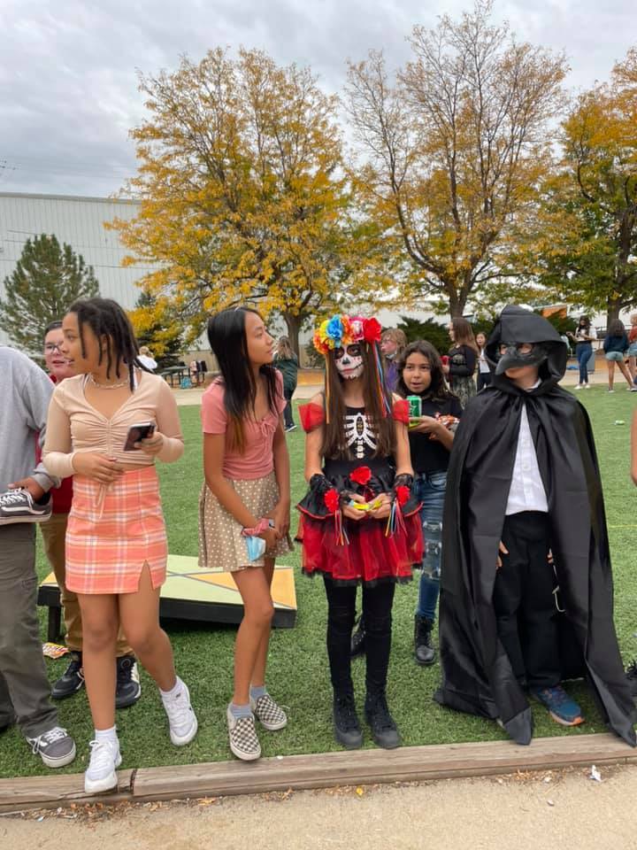 Students in costume line up and pose on sidewalk