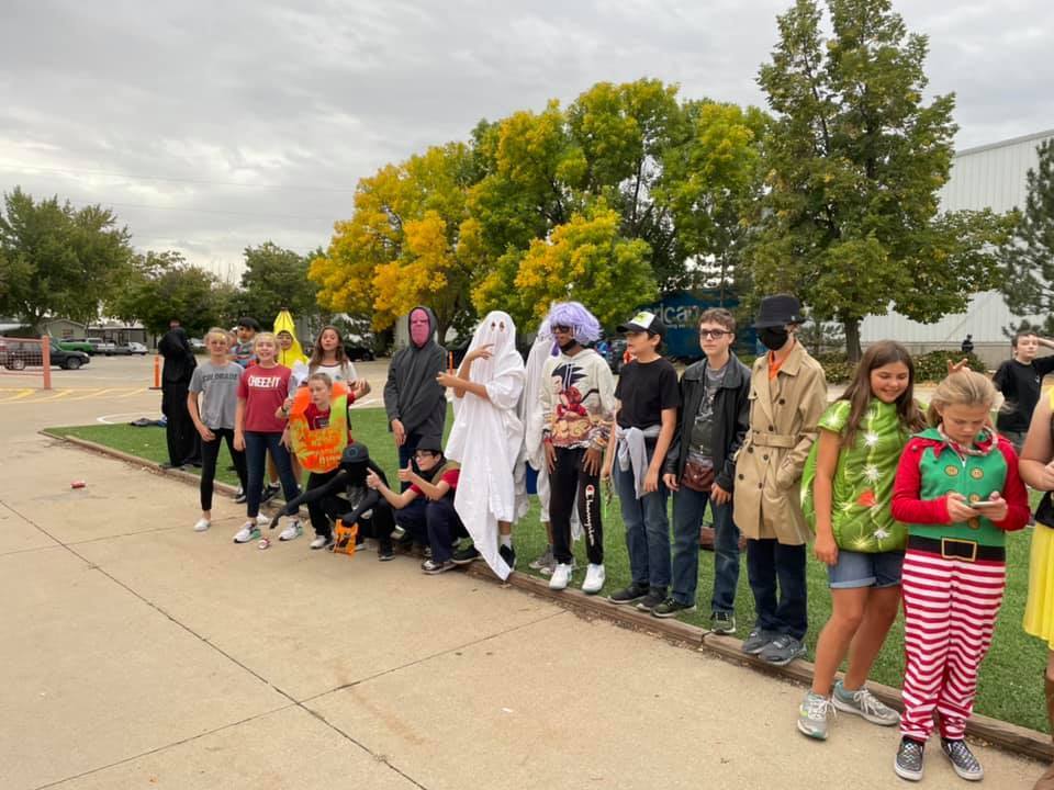 Students in costume line up and pose on sidewalk